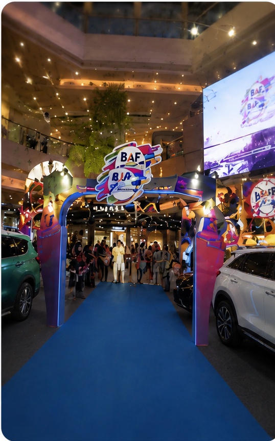 BAF Fair entrance with blue carpet, colorful arch, and display vehicles in mall atrium